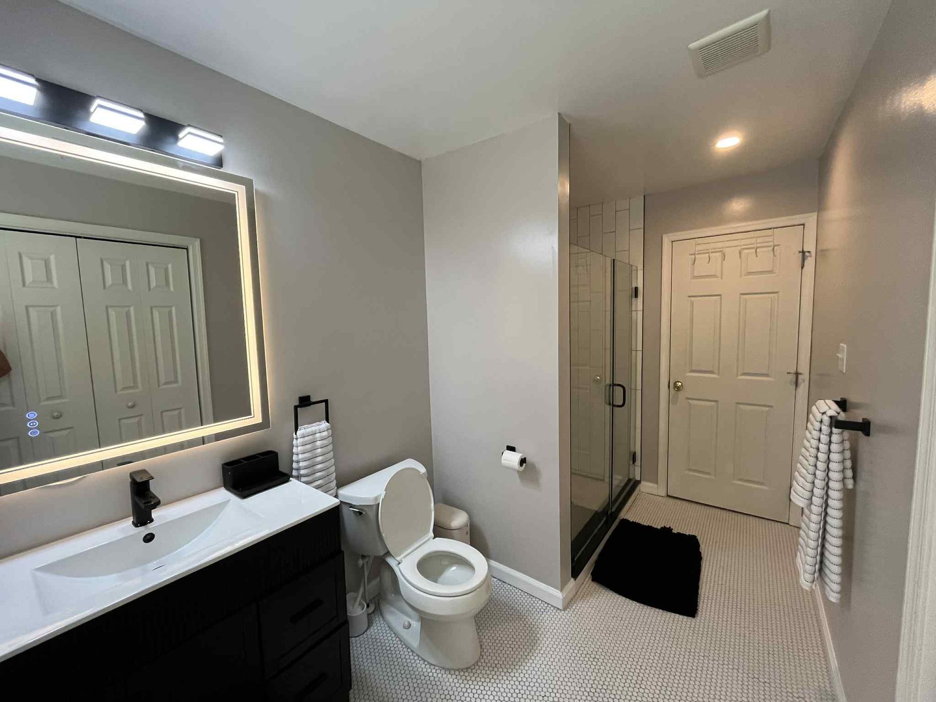 A bathroom with a toilet , sink and mirror.