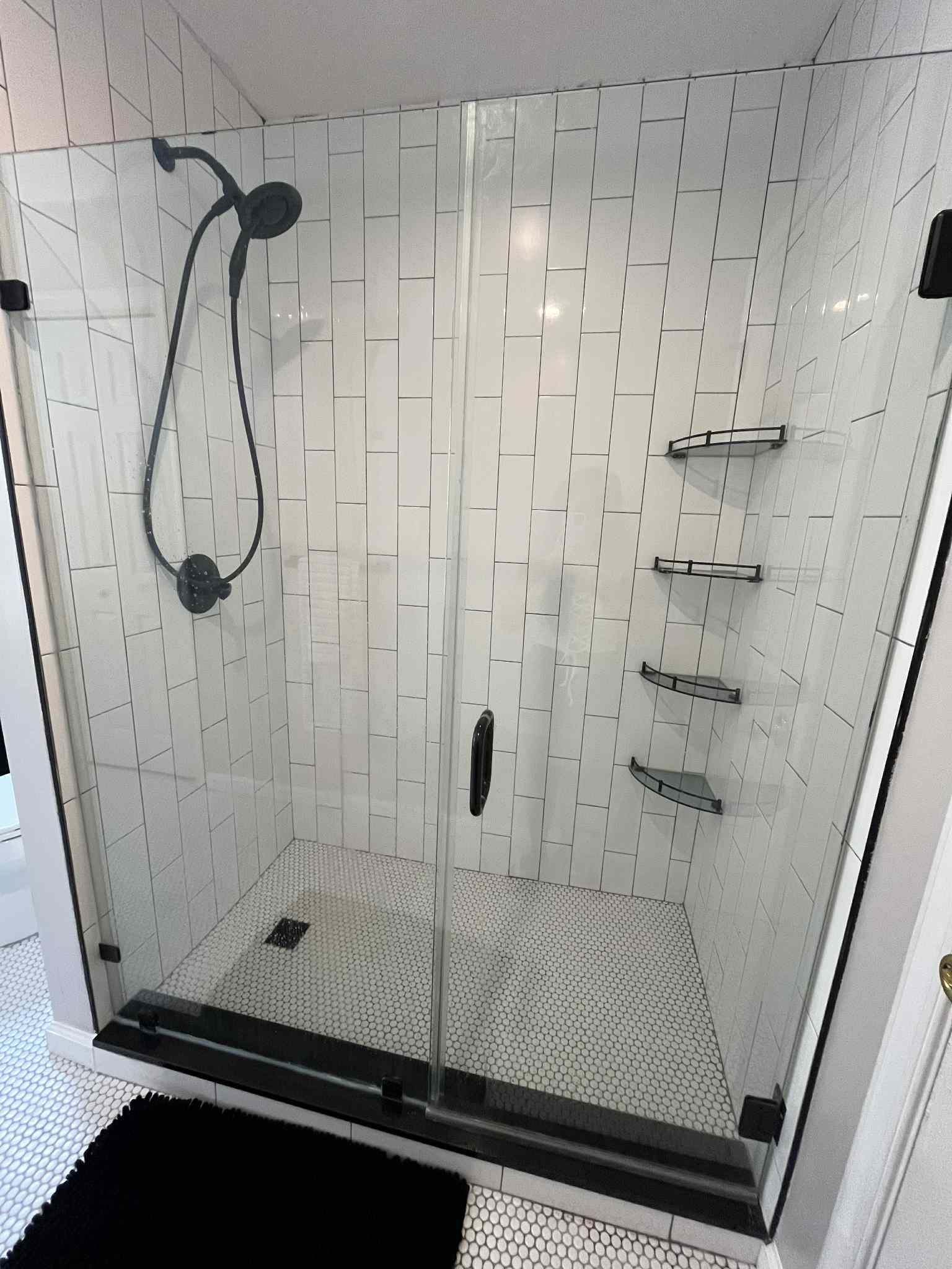 A bathroom with a walk in shower with a glass door.
