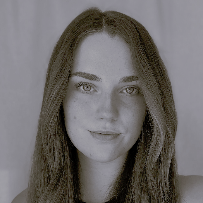 A woman with long hair is smiling in a black and white photo.