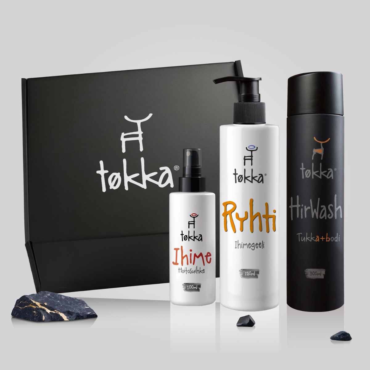 Three bottles of tokka products are sitting in front of a black box