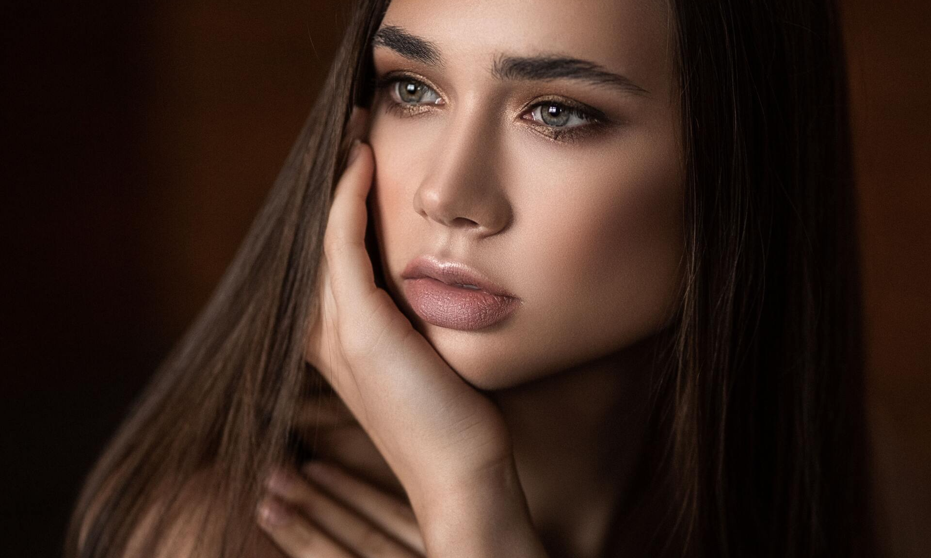 a close up of a woman 's face with her hand on her face .