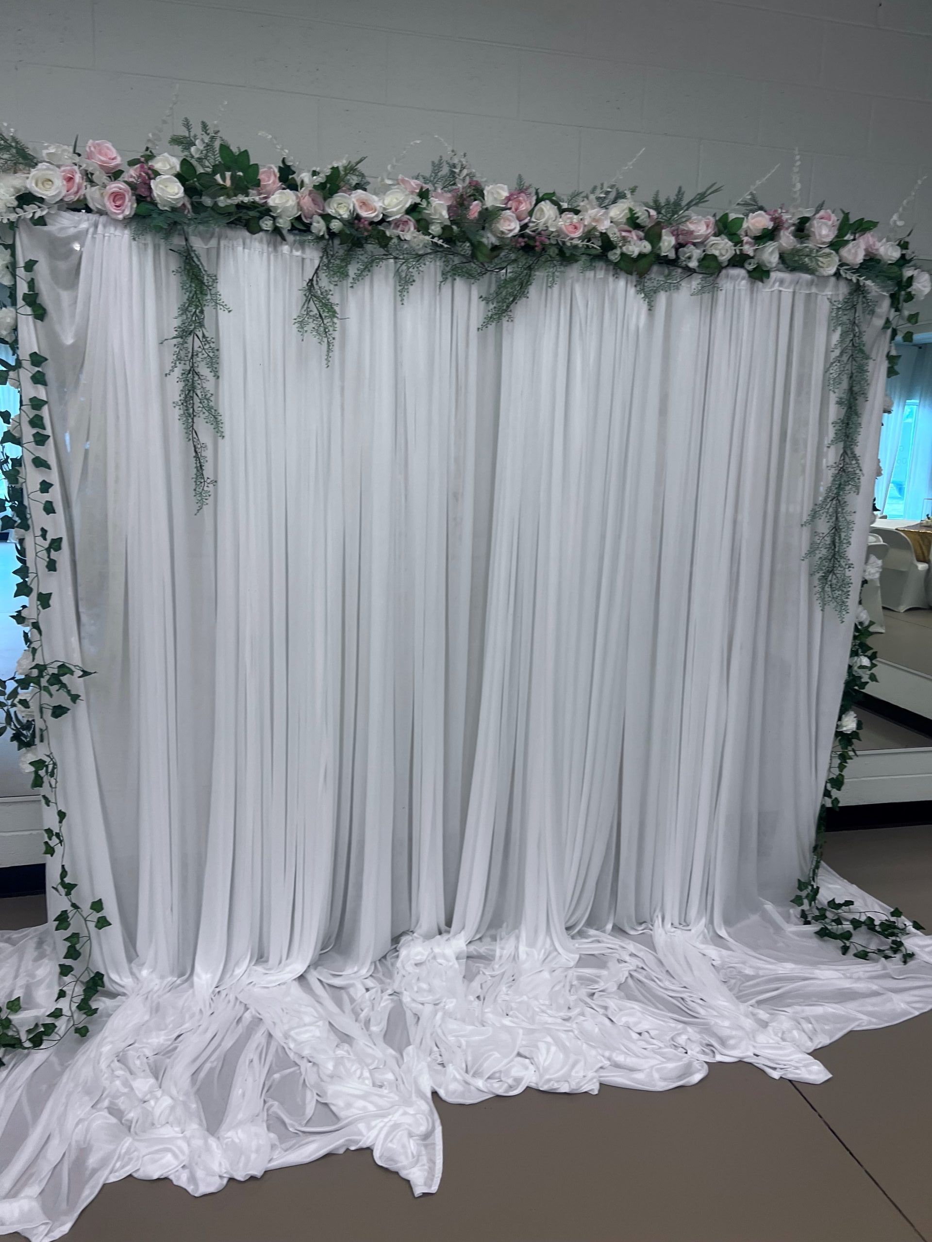 A white curtain with flowers on it is in a room.