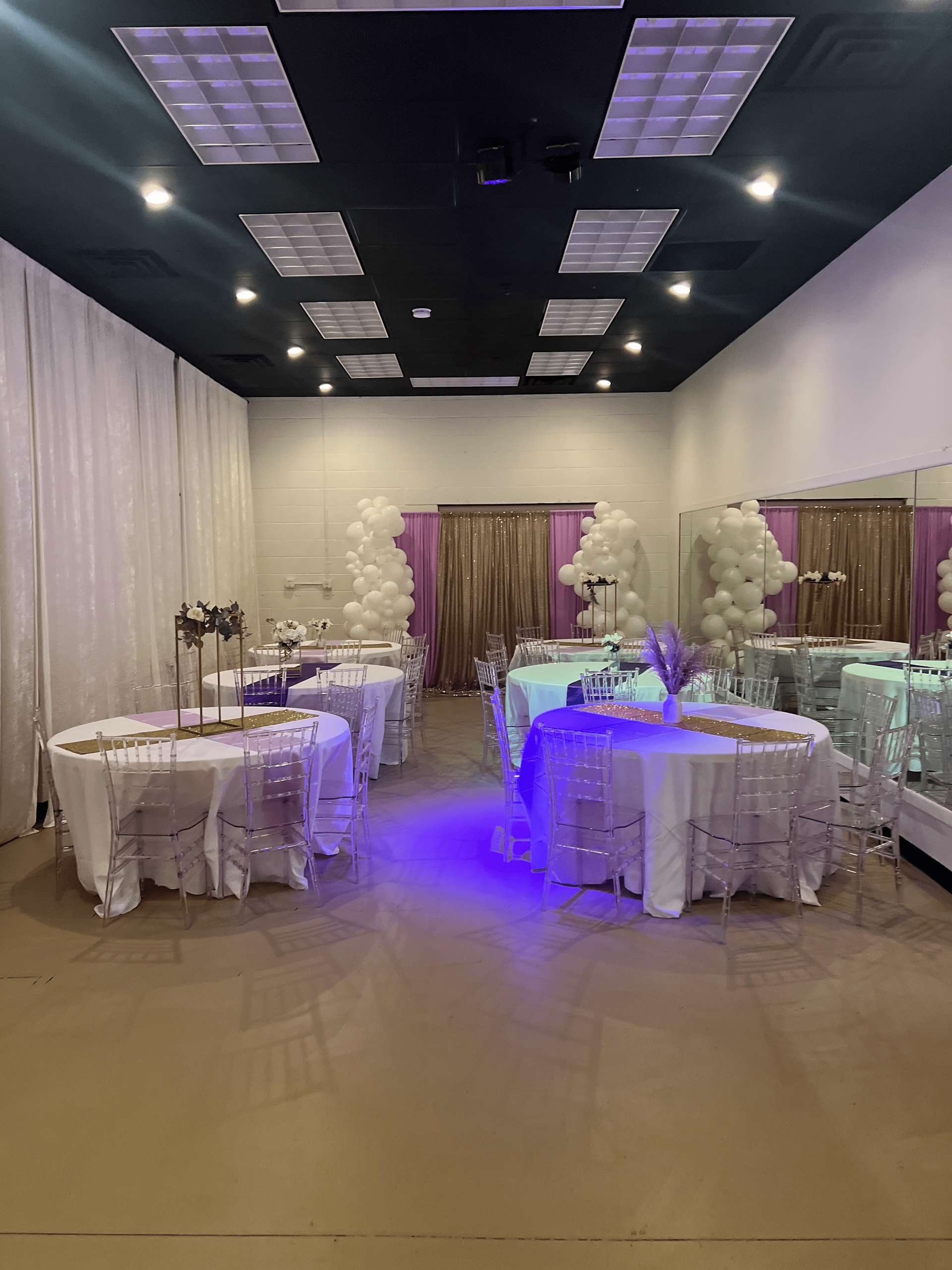 A large room with tables and chairs set up for a party.