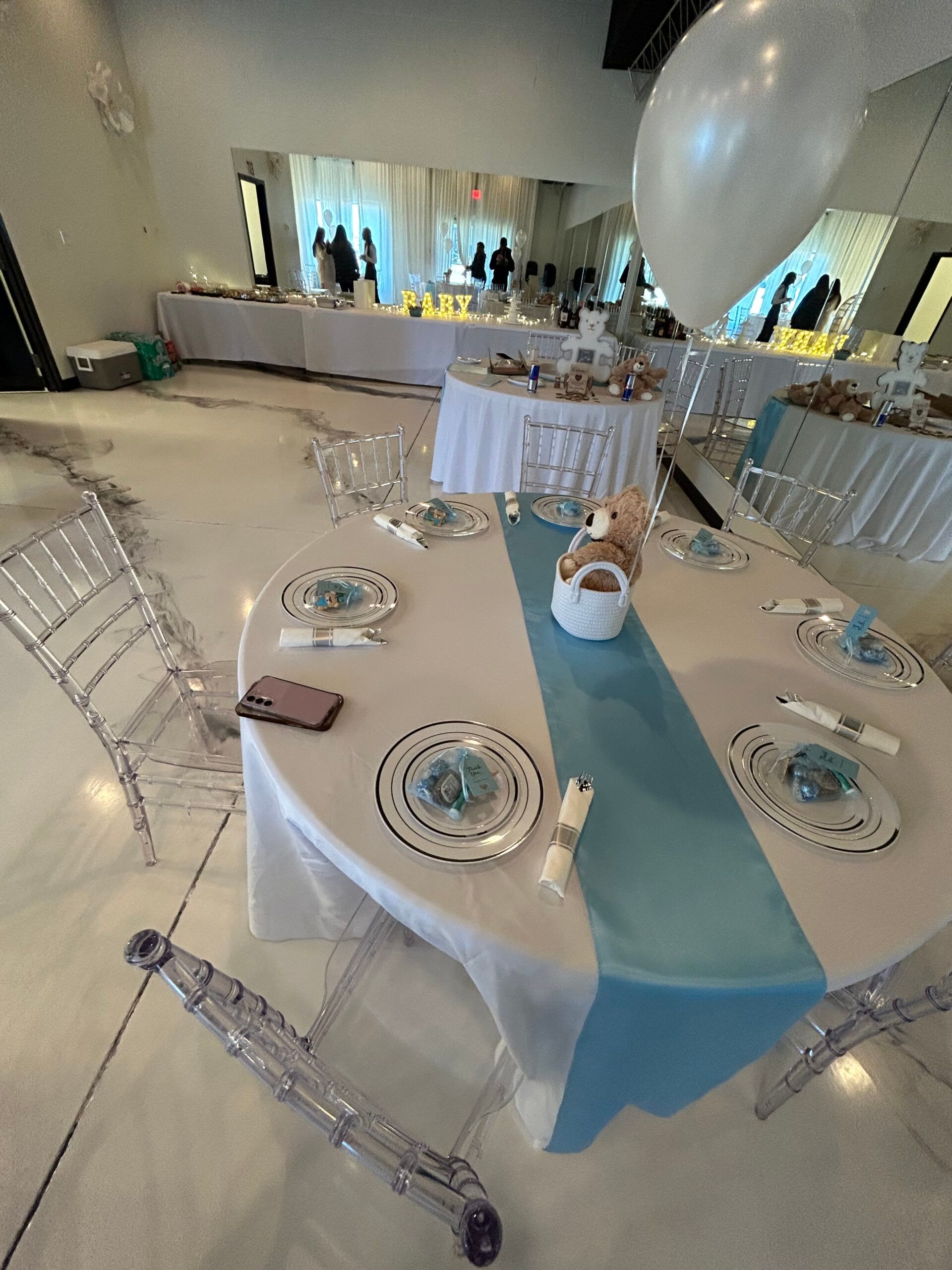 A table with plates and a blue table runner is set up for a party.