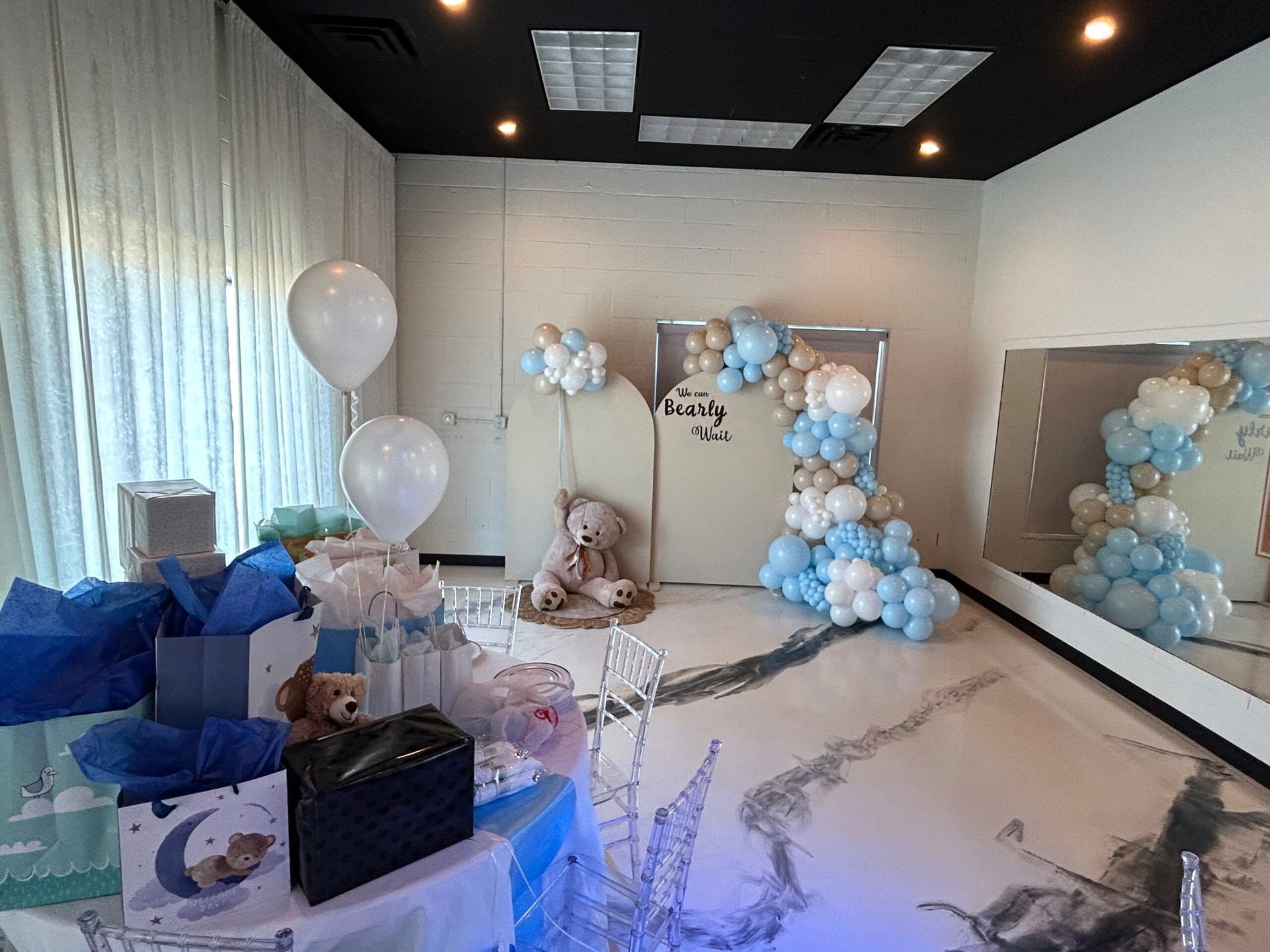 A room filled with balloons , gifts , and a teddy bear.