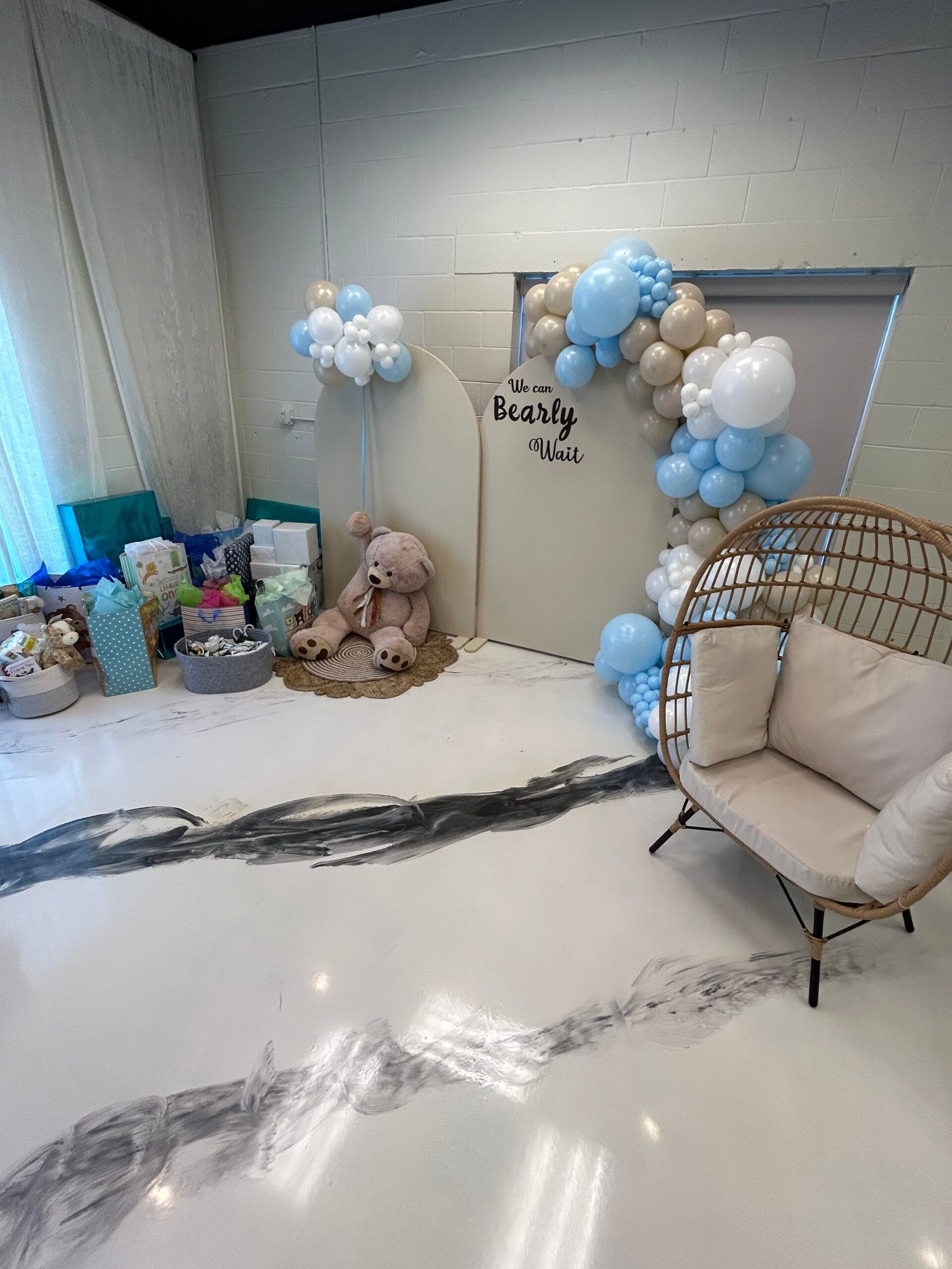 A room with a chair , balloons and a teddy bear.
