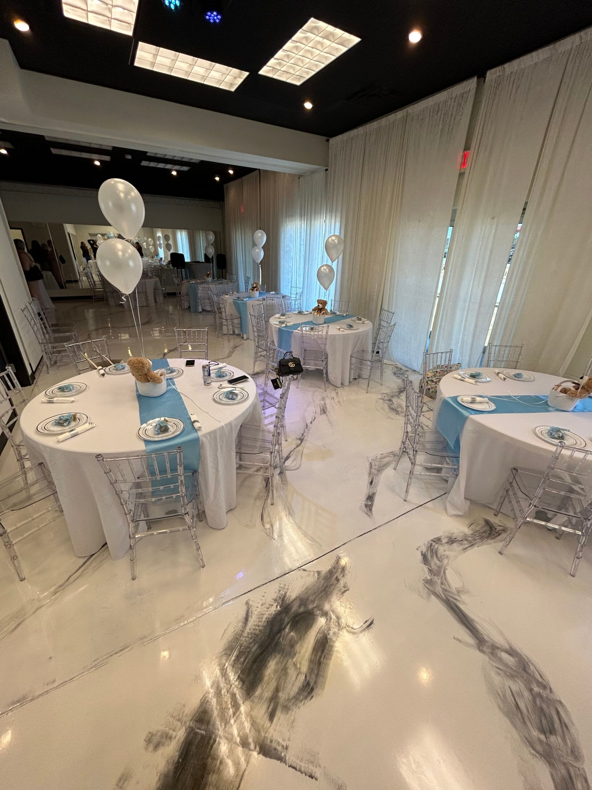 A large room filled with tables and chairs and balloons.