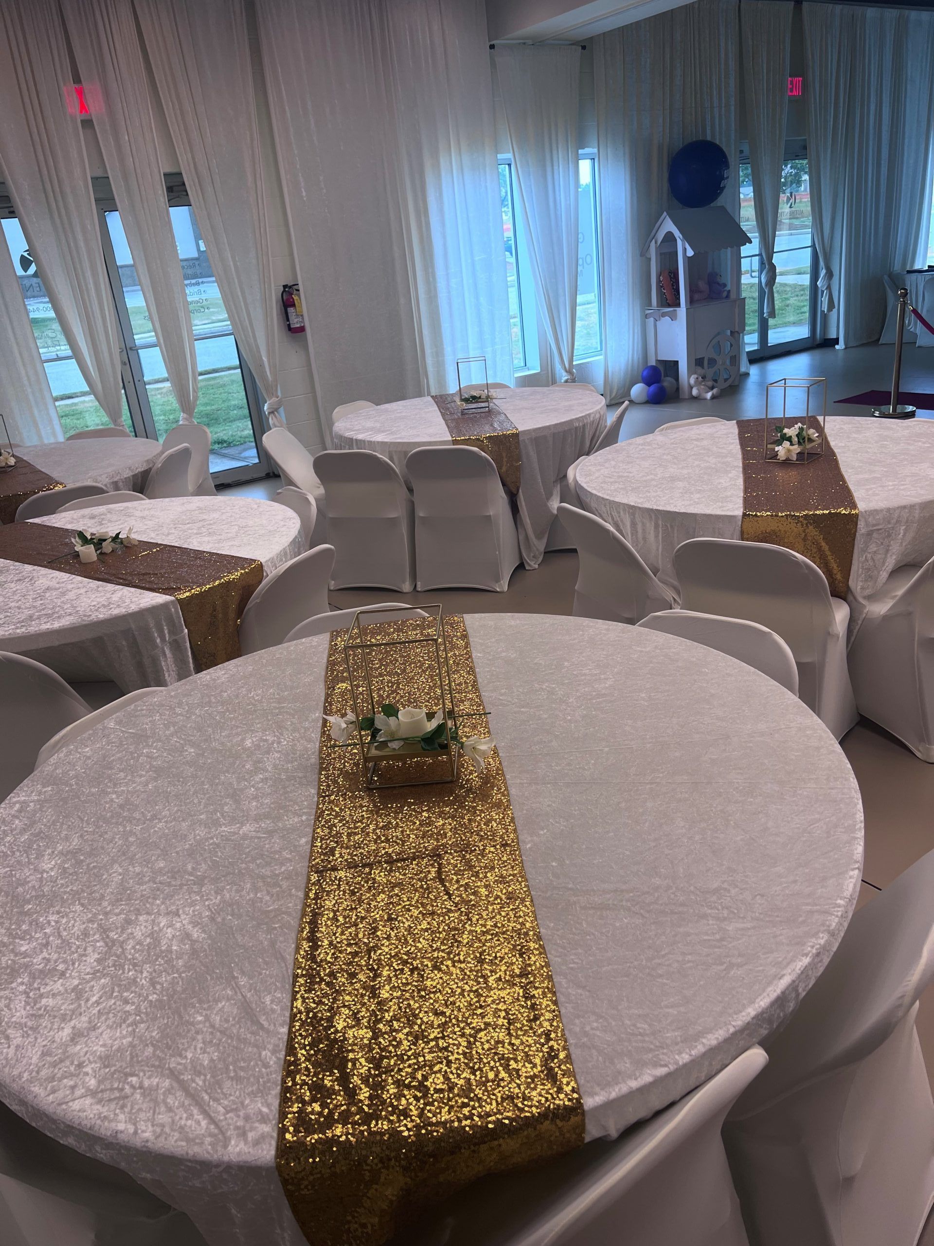A room with tables and chairs and a gold table runner