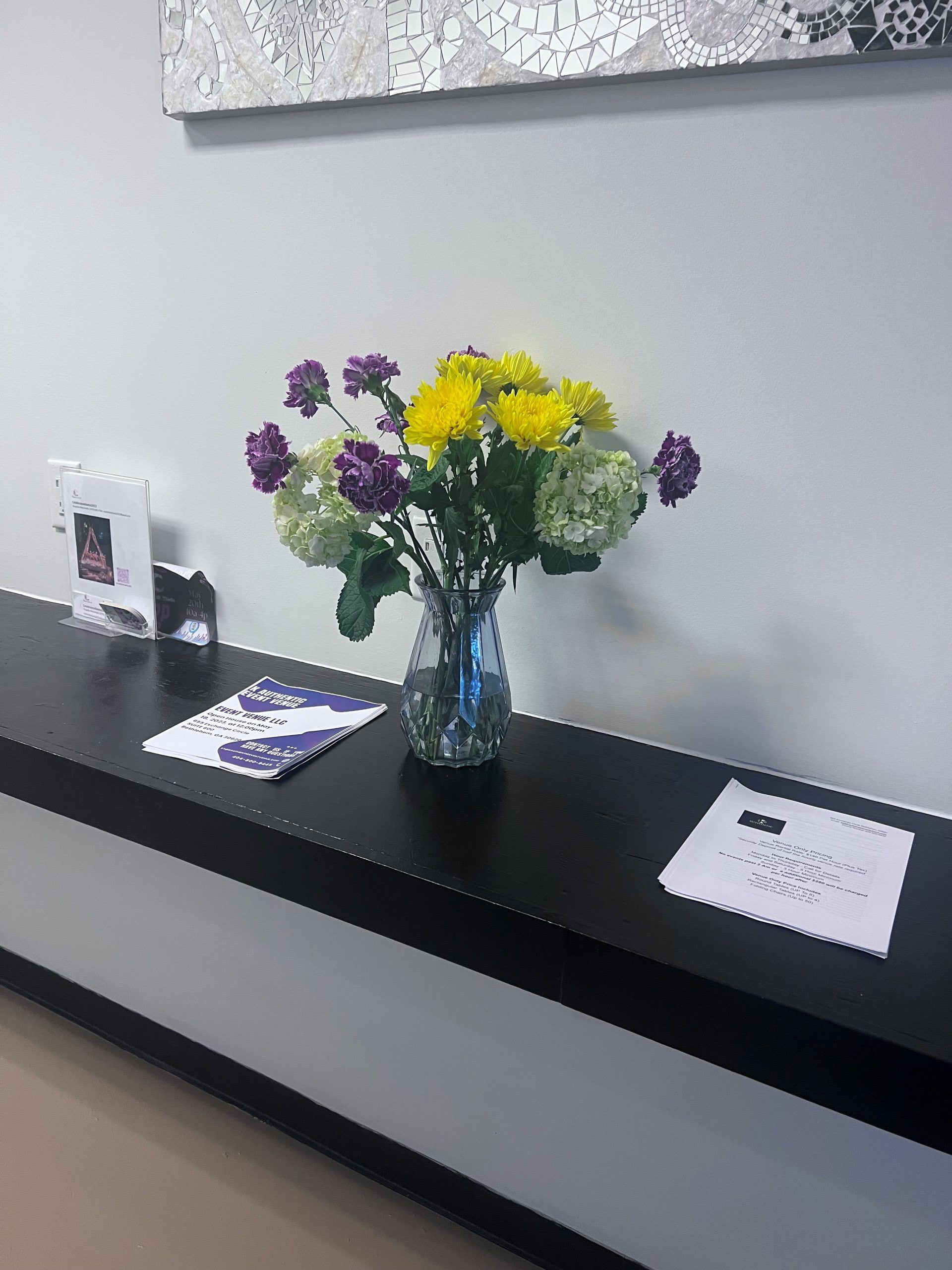 A vase of flowers sits on a black shelf