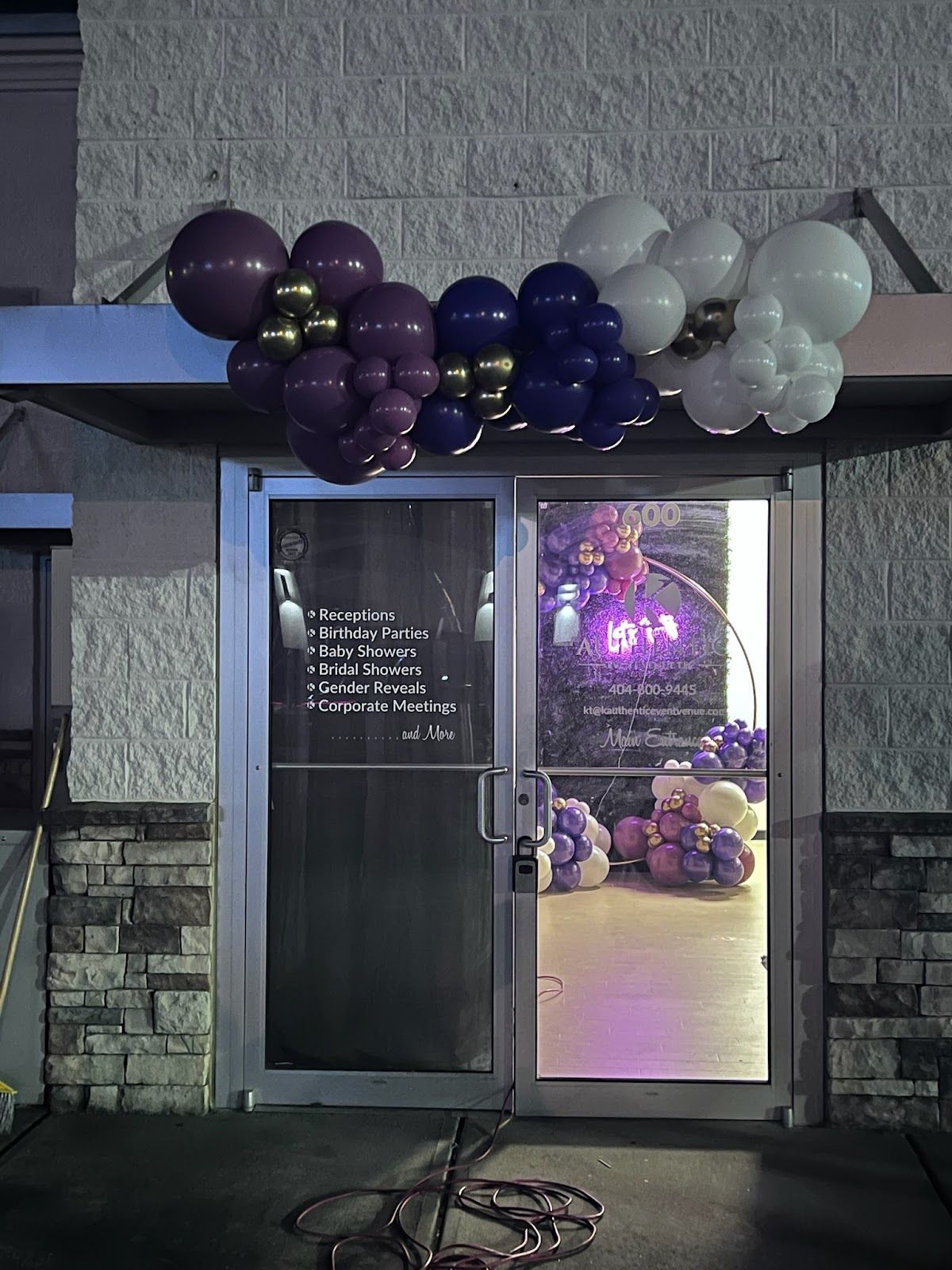 Purple and white balloons are hanging over the door of a building