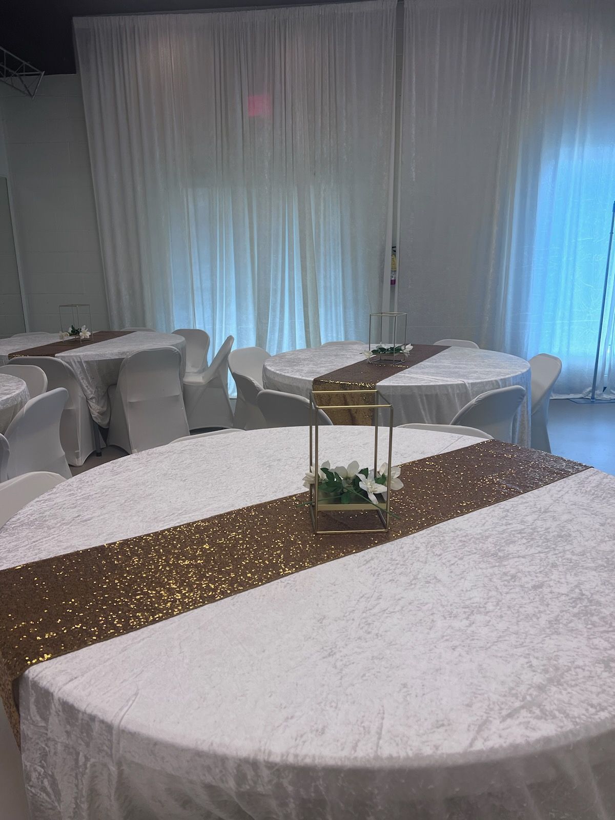 A room with tables and chairs set up for a wedding reception.