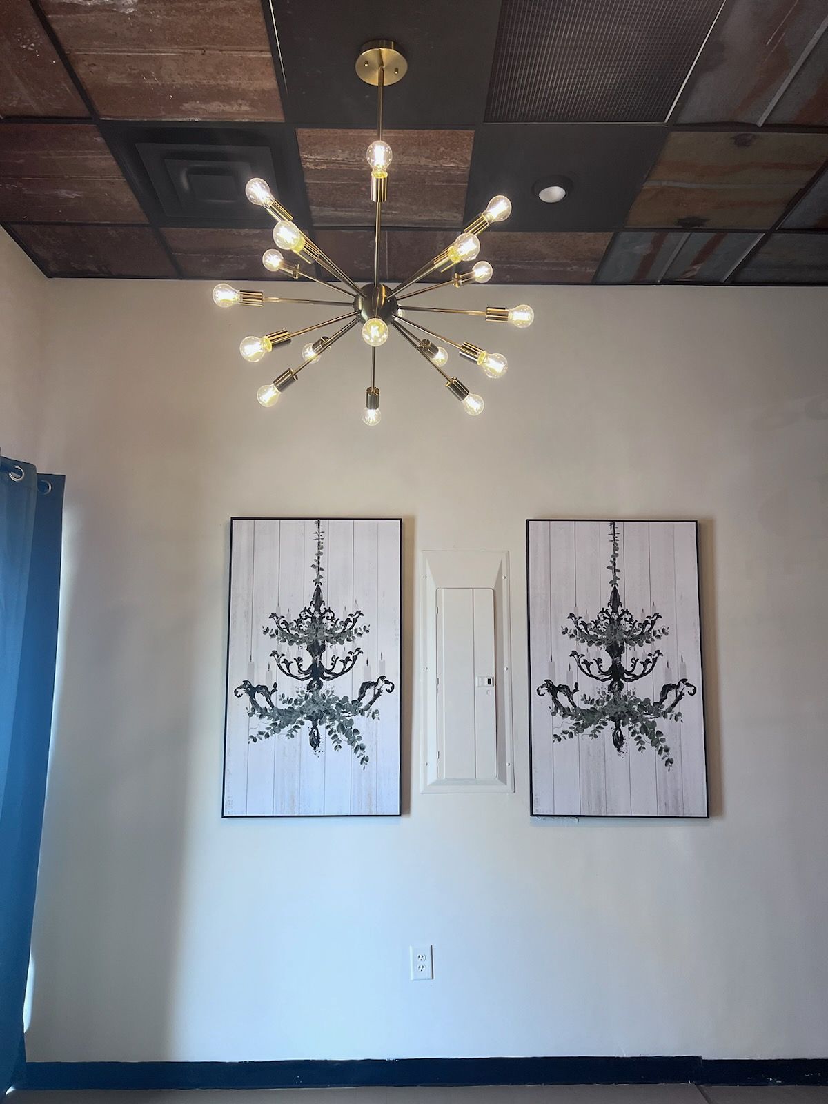 A room with two paintings and a chandelier hanging from the ceiling
