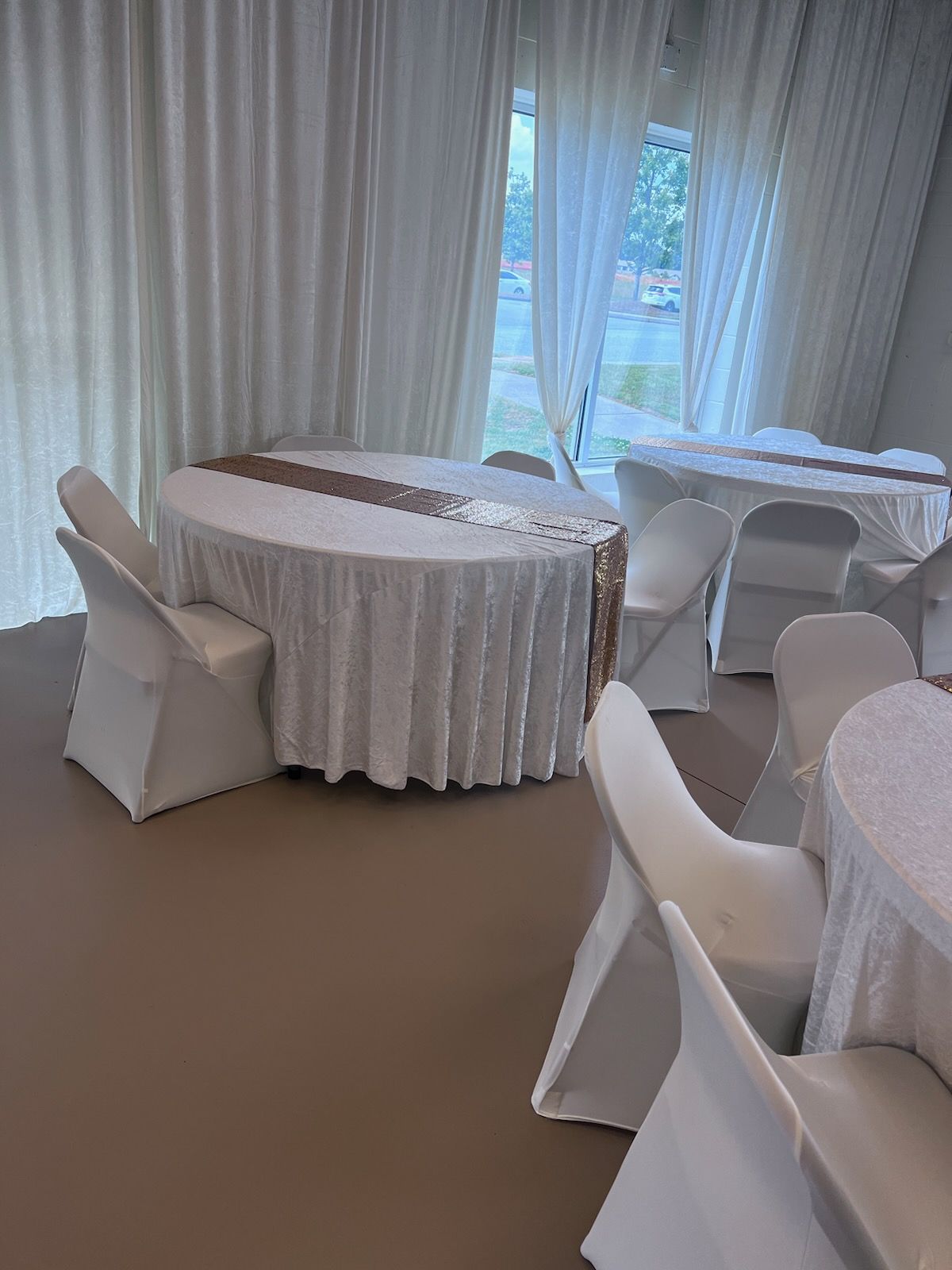 A room with tables and chairs set up for a wedding reception.