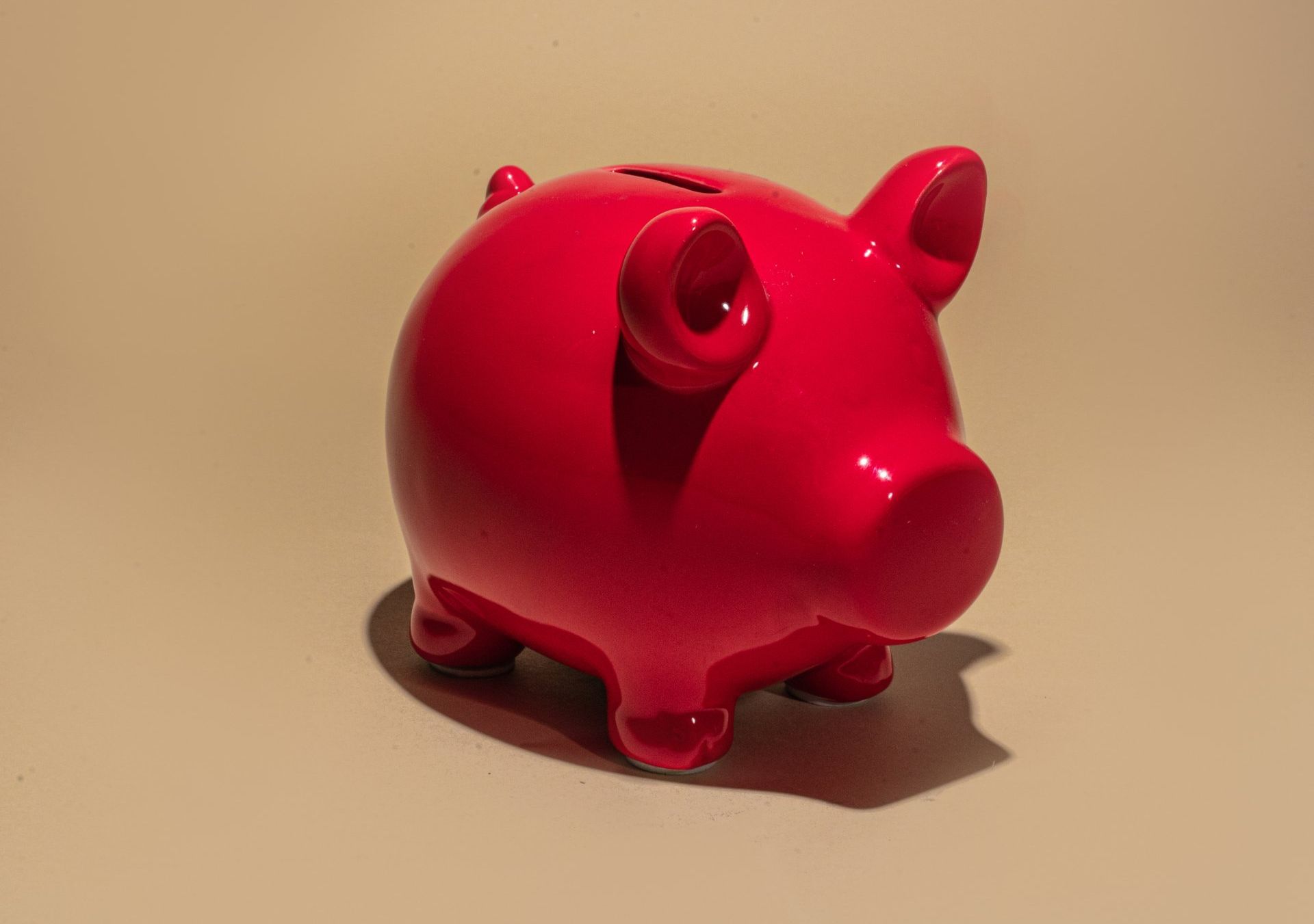 a red piggy bank is sitting on a beige surface .
