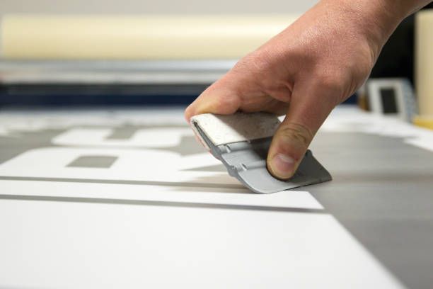 Hand using a squeegee to apply a white decal.