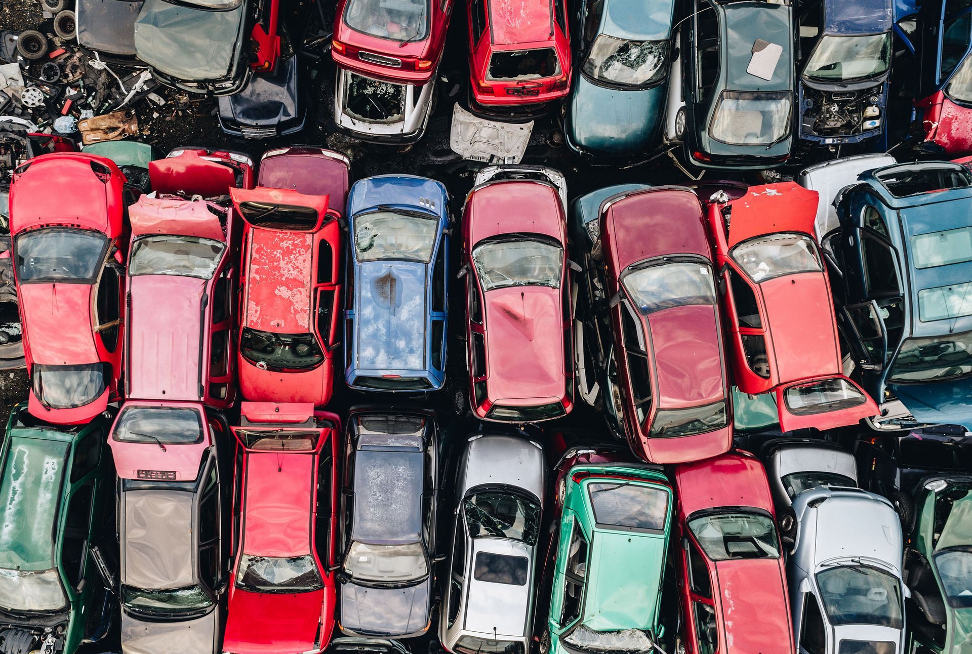 Overhead view of a car graveyard filled with colorful, wrecked vehicles.