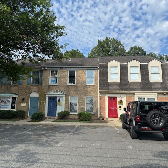 Row of townhouses with different colored doors, parked car in front.