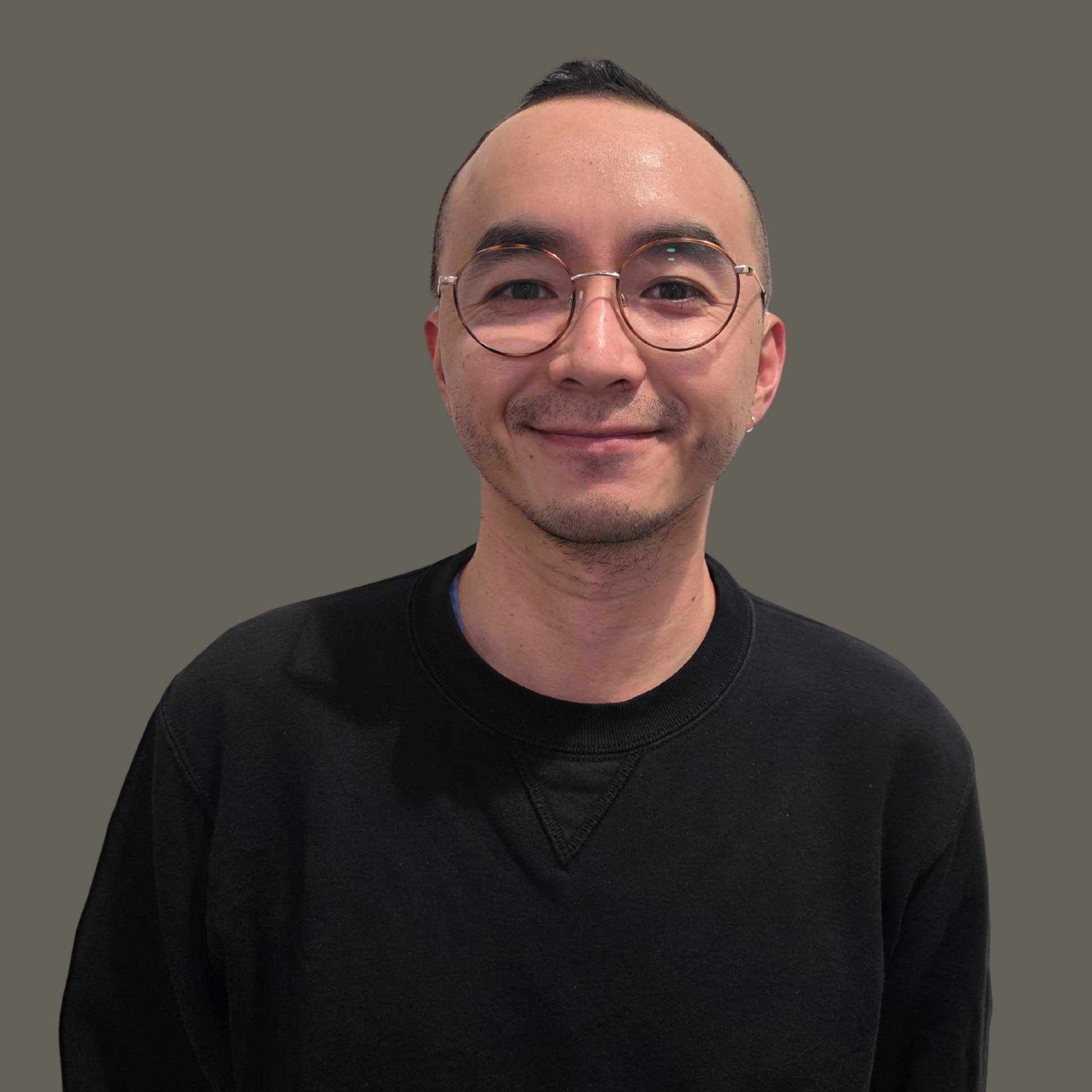 Man standing in front of a solid wall smiling