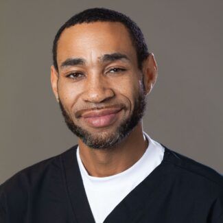 Man standing in front of a solid wall smiling