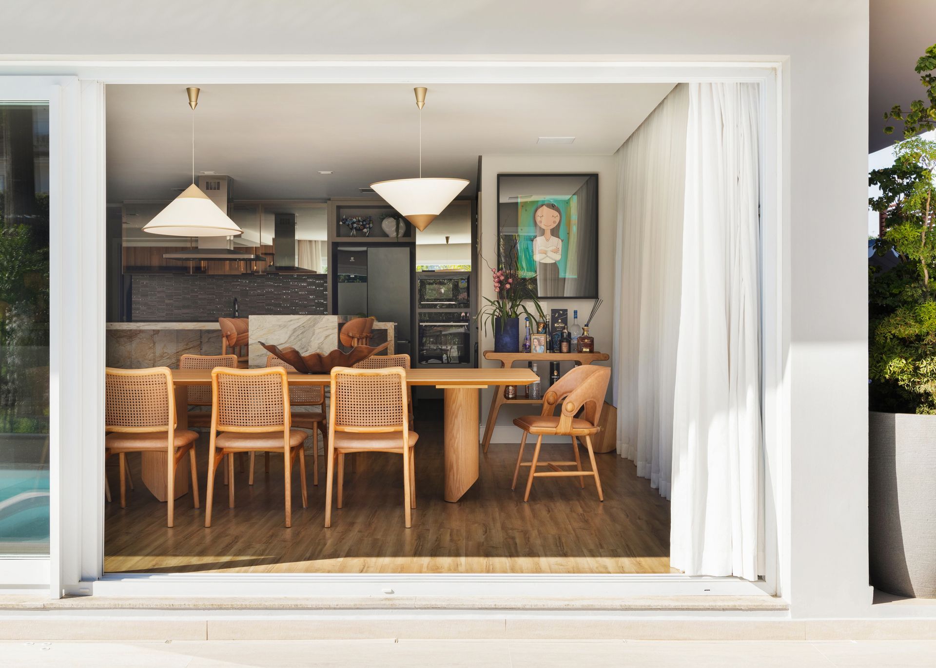 Uma sala de jantar com mesa e cadeiras é visível através de uma porta de vidro deslizante.