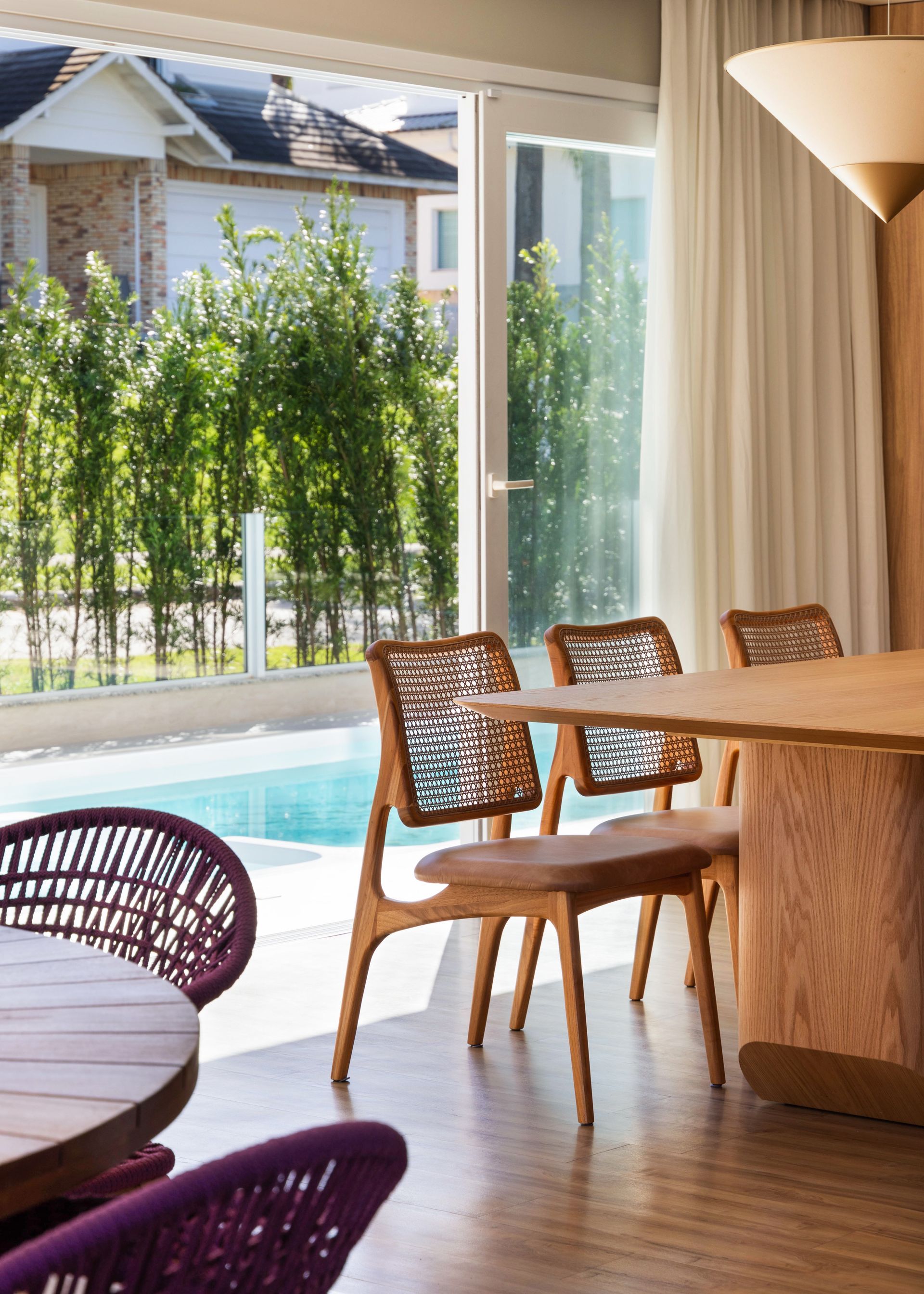 Uma sala de jantar com mesa e cadeiras e vista para a piscina.