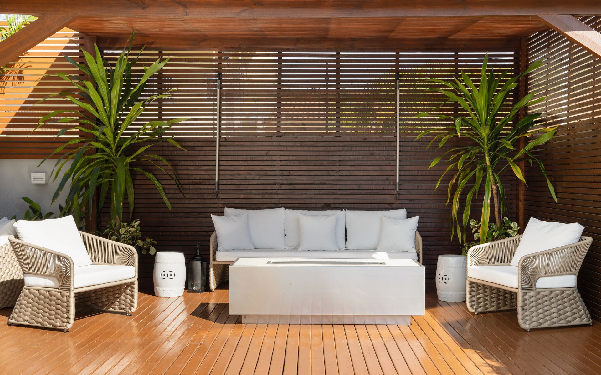 Um deck de madeira com um sofá, cadeiras e uma mesa.