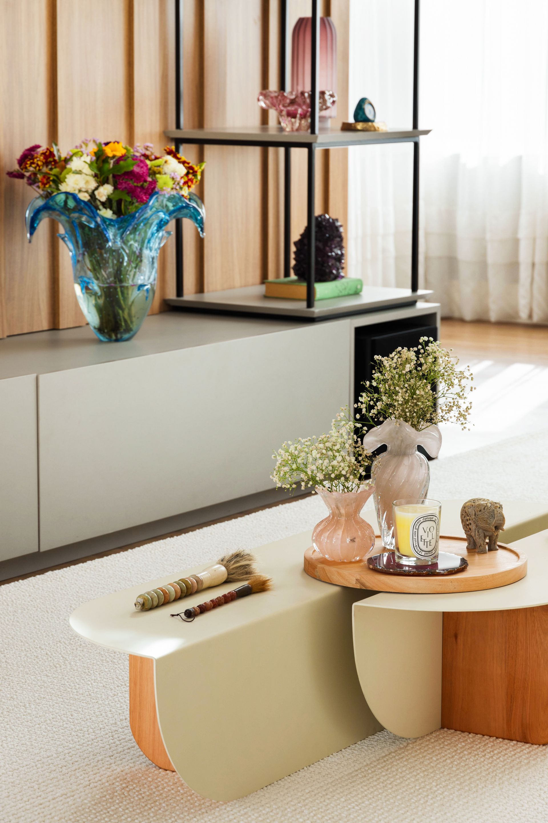 Uma sala de estar com duas mesas de centro e um vaso de flores sobre a mesa.