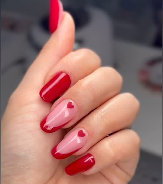 Mano con nail art rossa e rosa raffigurante un cuore.