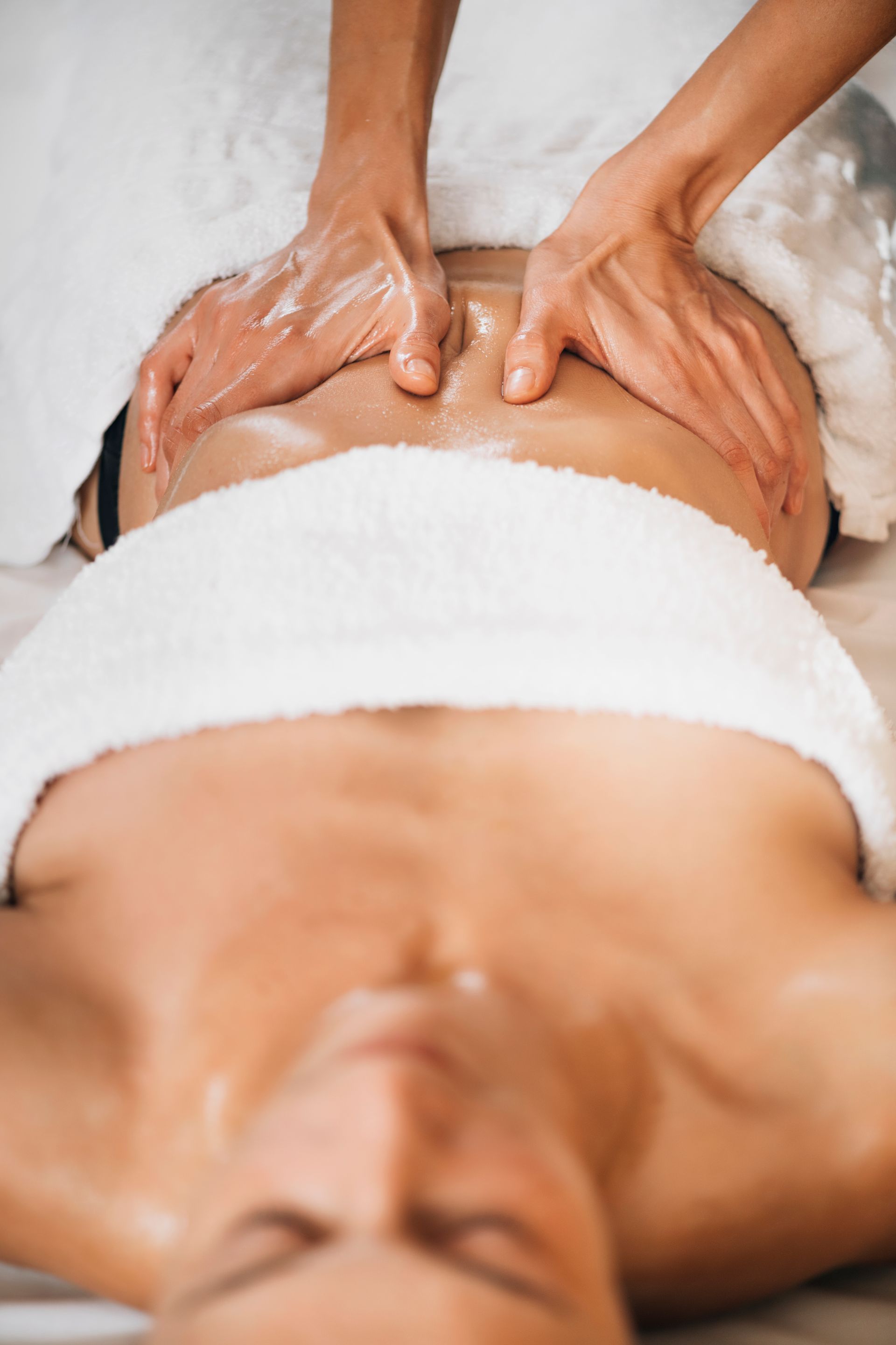 Persona che riceve un massaggio alla schiena con le mani che applicano l'olio.