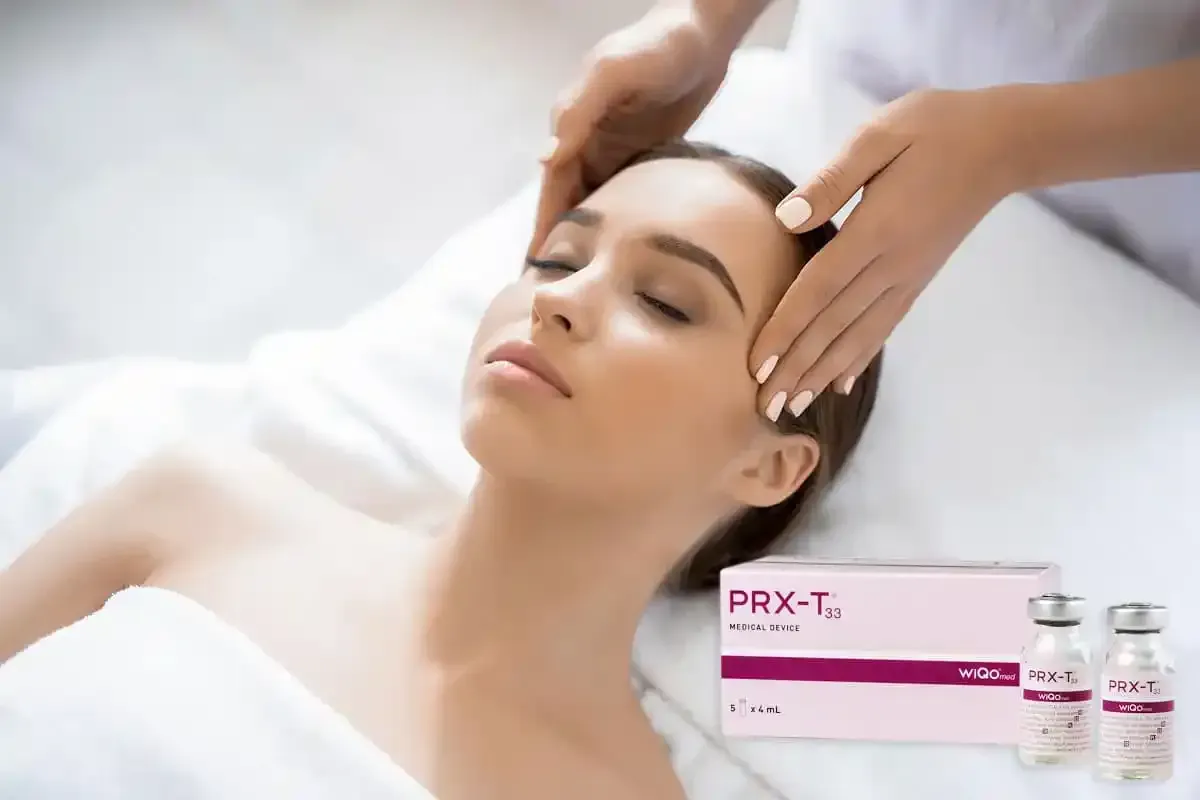 Donna che riceve un trattamento viso, mani sulla fronte; prodotti per la cura della pelle PRX-T33 visibili.