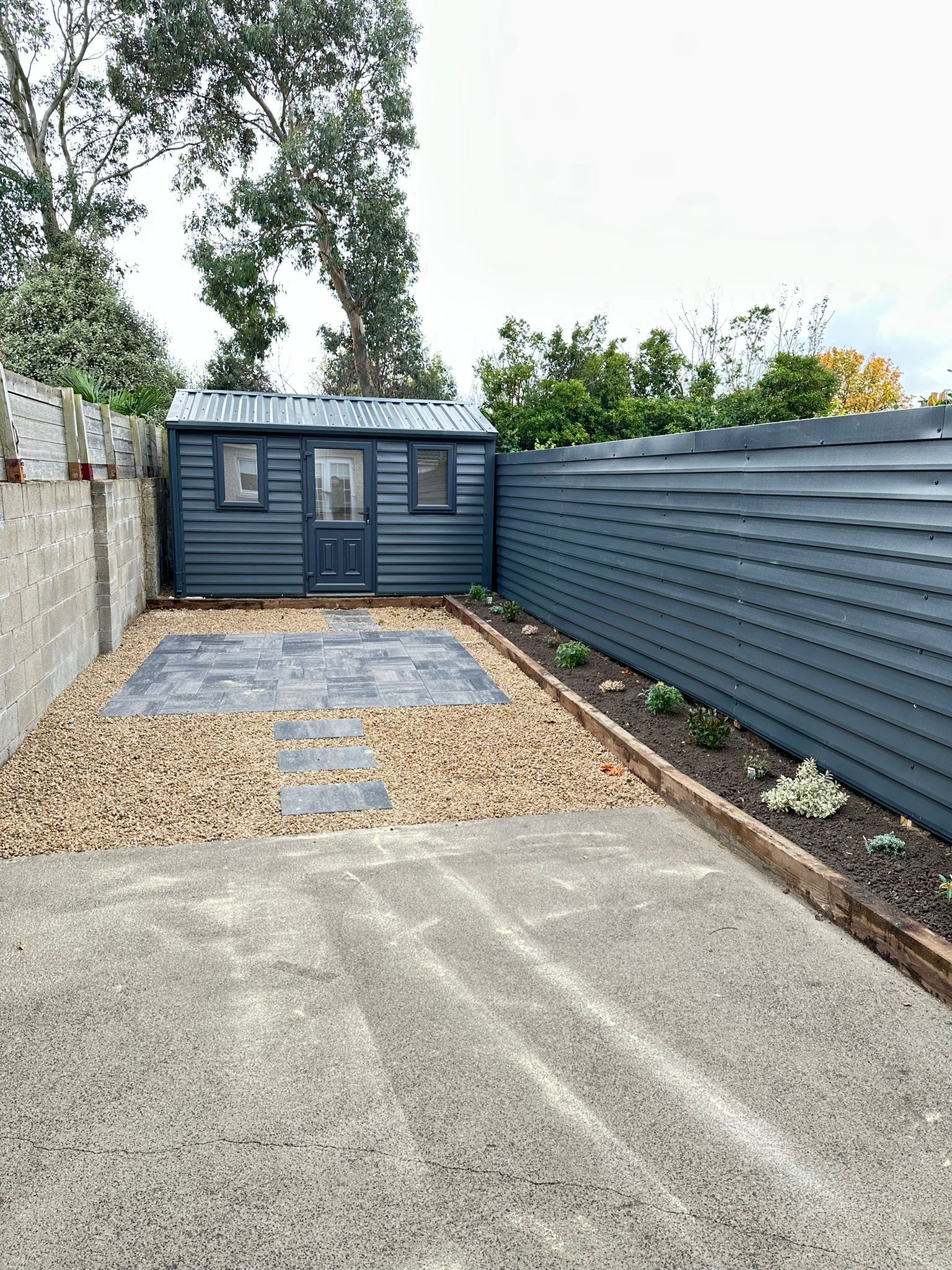 A shed is sitting in the backyard of a house next to a fence.