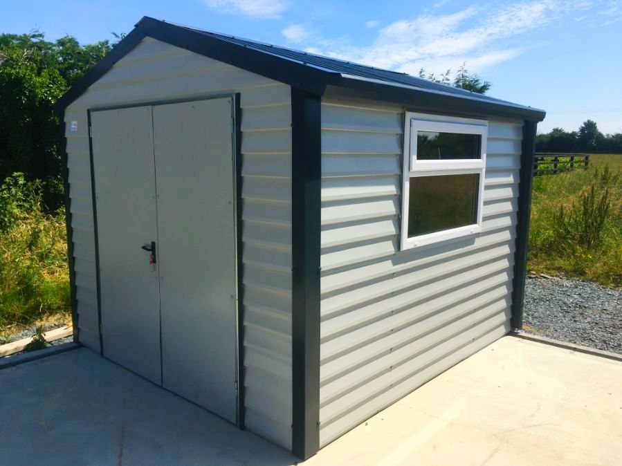 A white shed with a black roof and a window