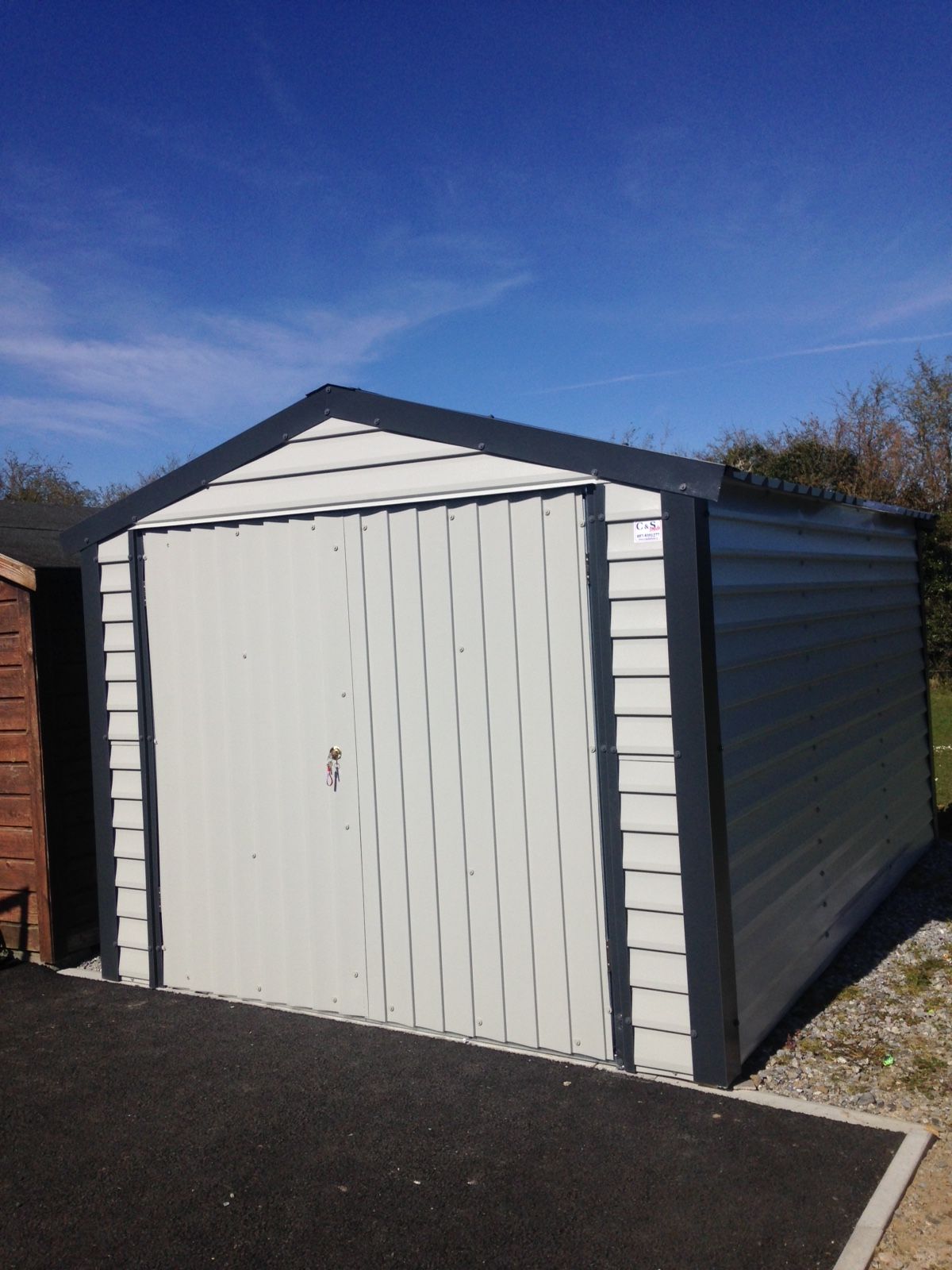 A white garage with a black trim and a blue sky in the background