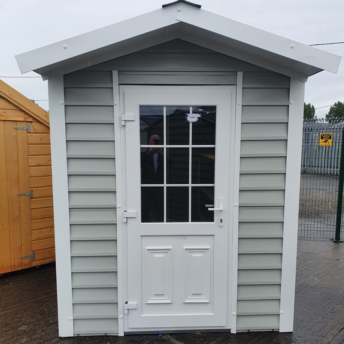 A small white shed with a glass door