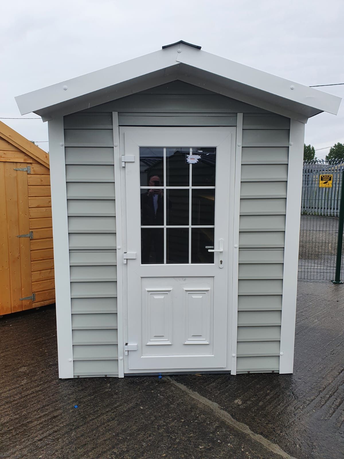 A small white shed with a white door and window.