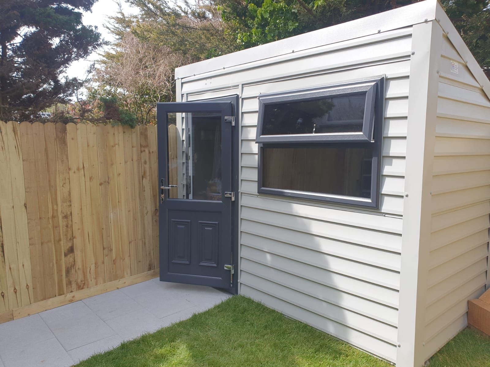 A white shed with a black door and window