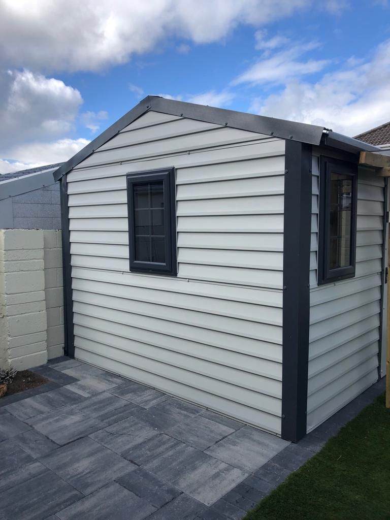 A white shed with a window on the side of it.