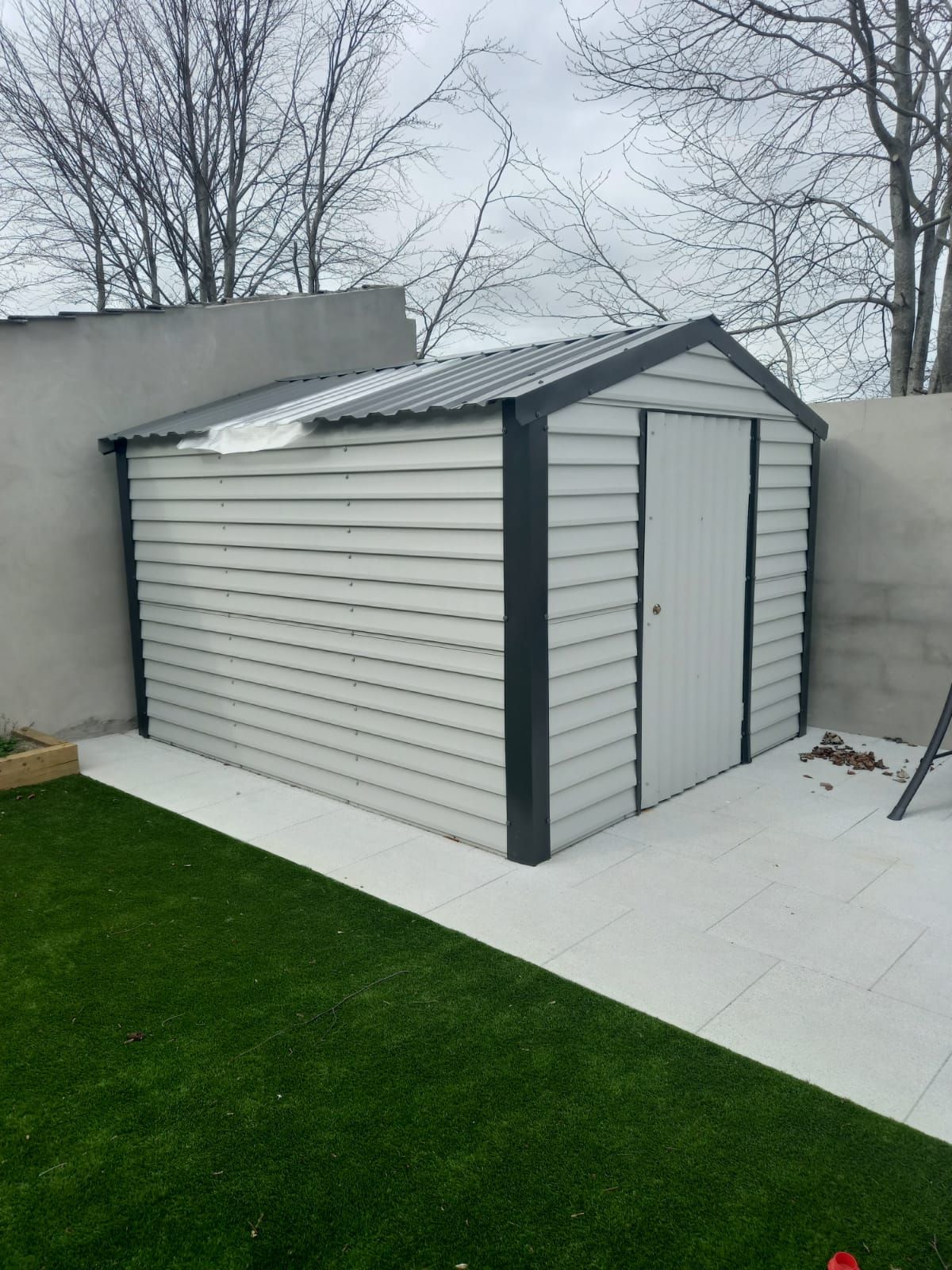 A white shed is sitting on top of a lush green lawn.