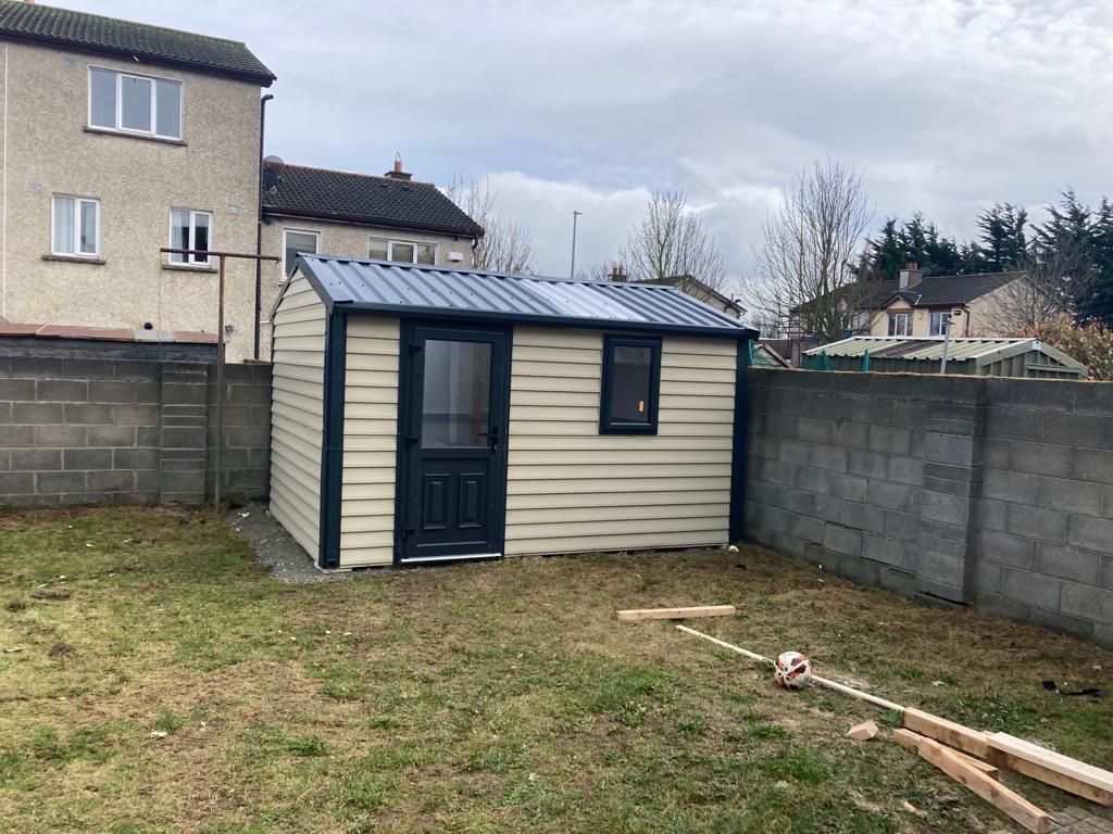 A small shed in a backyard next to a brick wall.