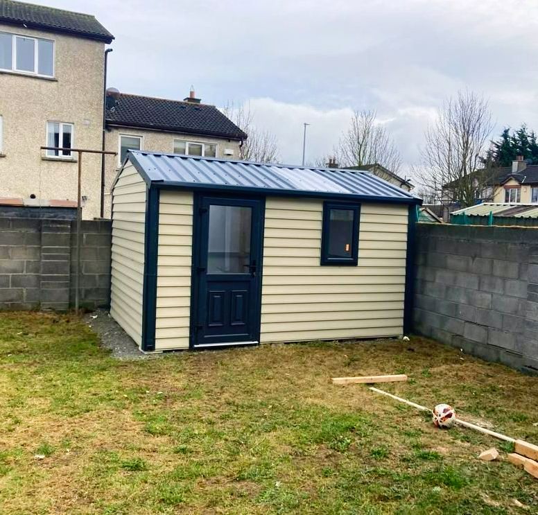 A small shed in a backyard with a brick wall behind it