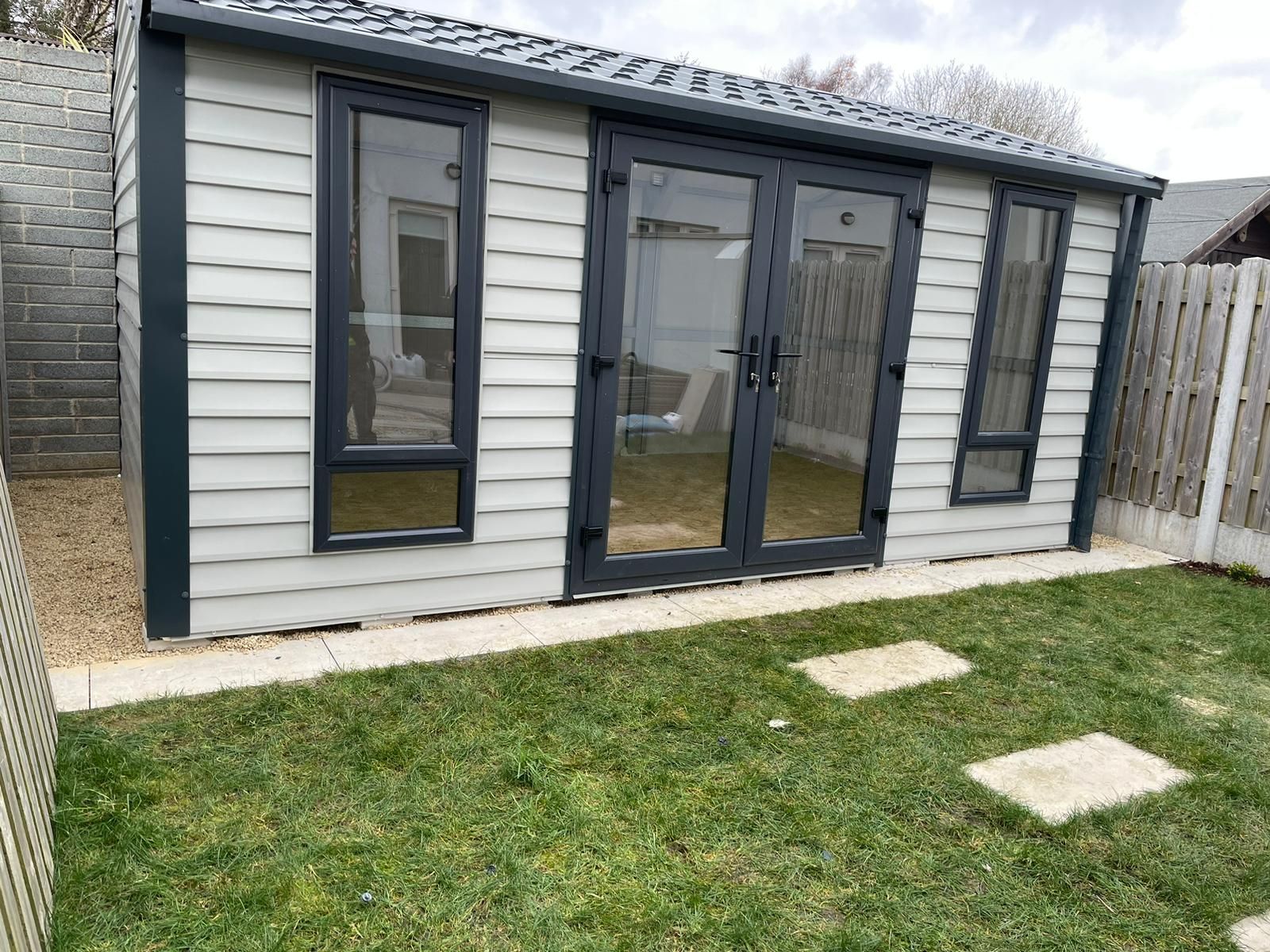 A small house with a lot of windows and doors in a backyard.