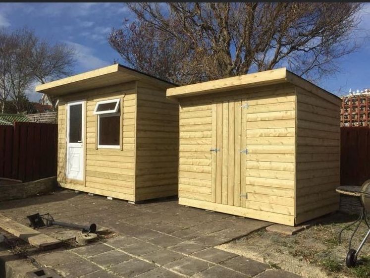 Two wooden sheds are sitting next to each other in a backyard.