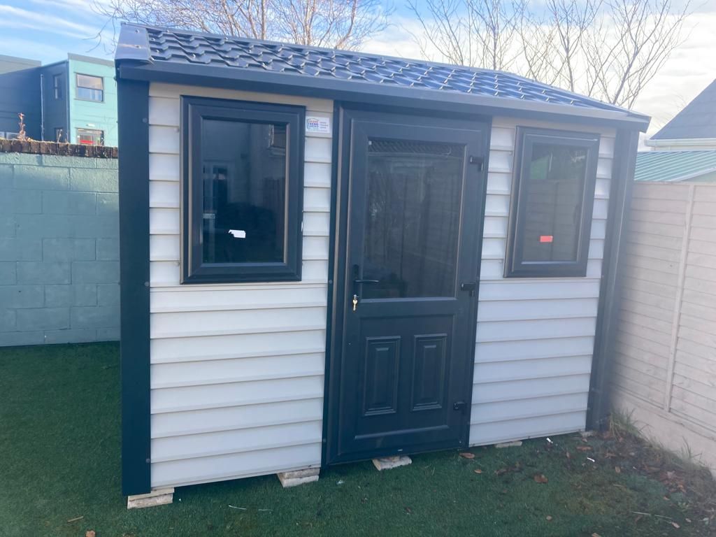 A small white shed with a black door and windows