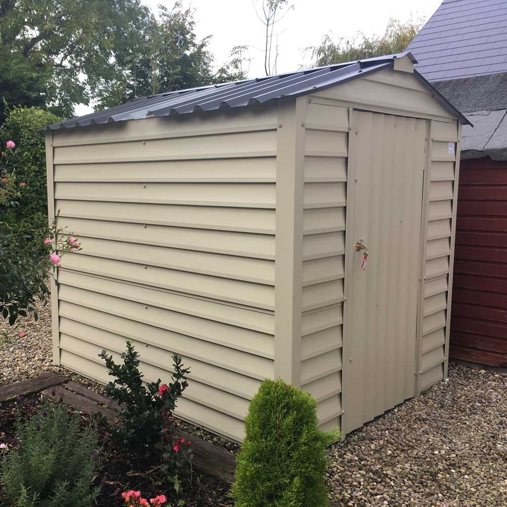 A white shed with a black roof sits next to a red shed