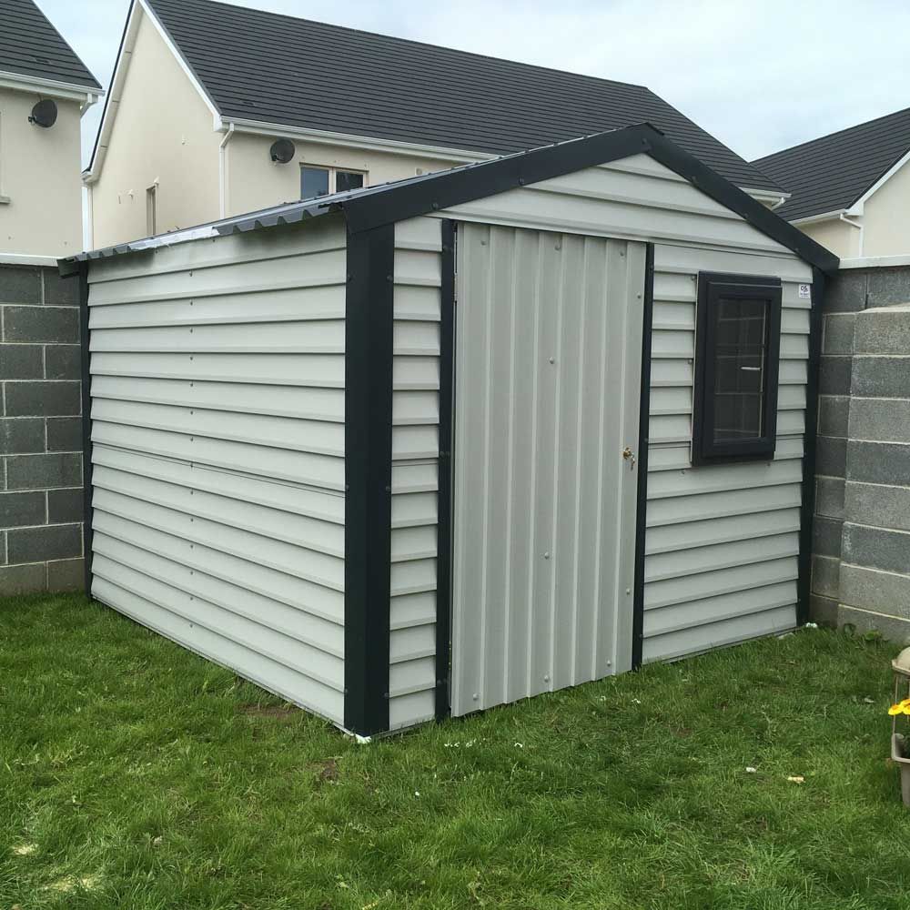 A white shed with a black trim sits in the grass