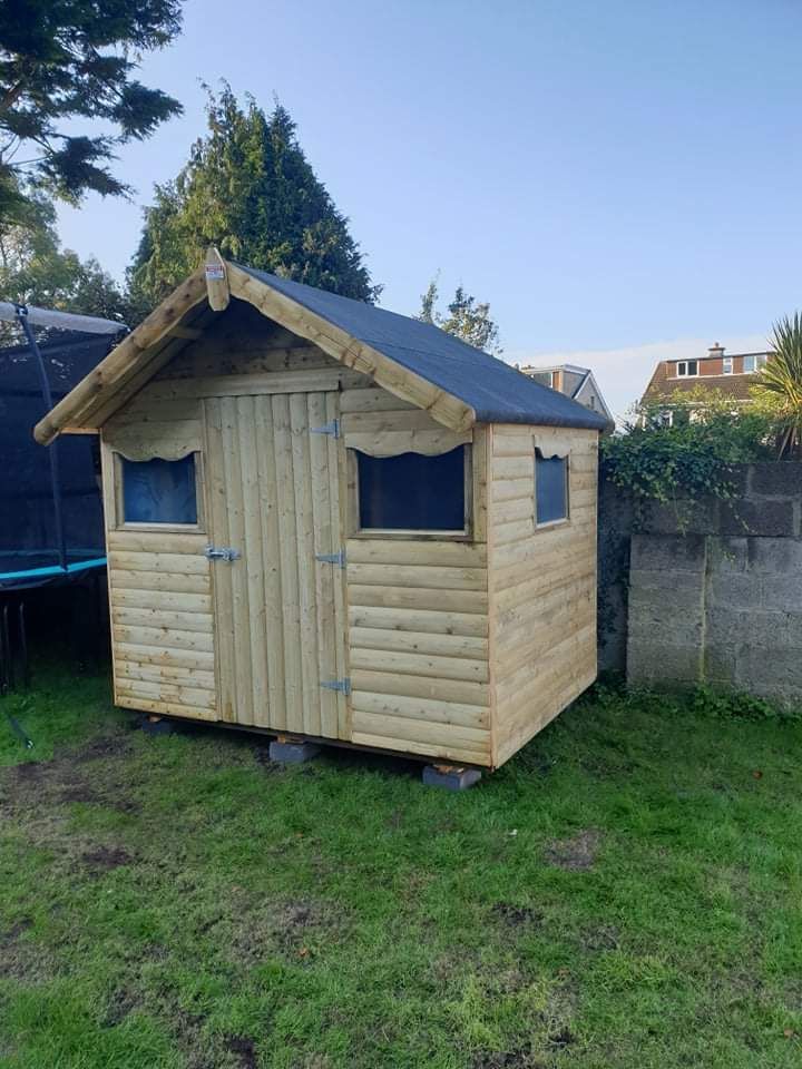 A small wooden shed is sitting in the middle of a lush green field.