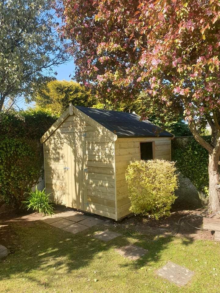 A wooden shed is sitting in the middle of a lush green garden.