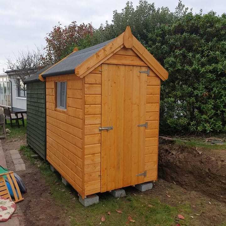 A small wooden shed with a black roof and a window