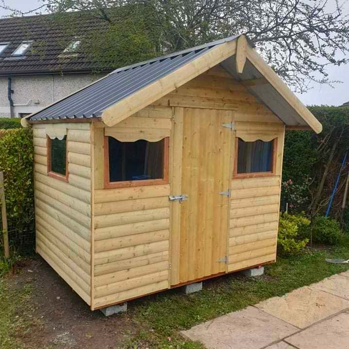 A small wooden shed with a blue roof is sitting in the grass.