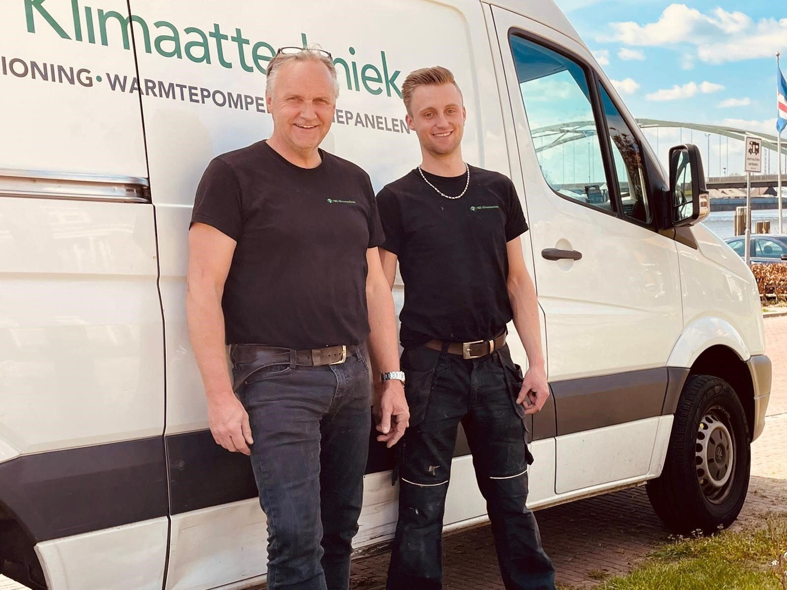 Twee mannen staan naast een wit busje.